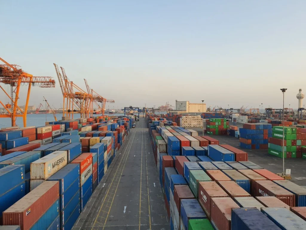 A bustling international trade port with colorful cargo containers at sunrise.